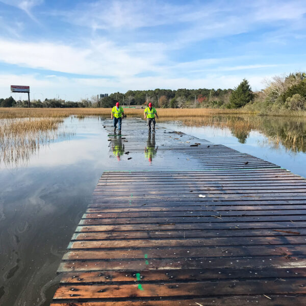 team members walking across wooden bridge on water