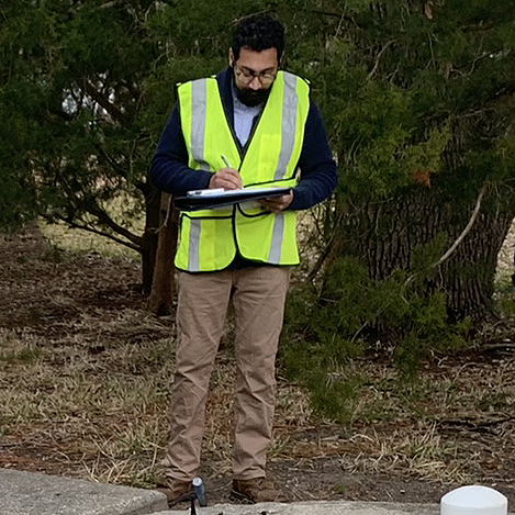 Danial working in the field with yellow safety vest on